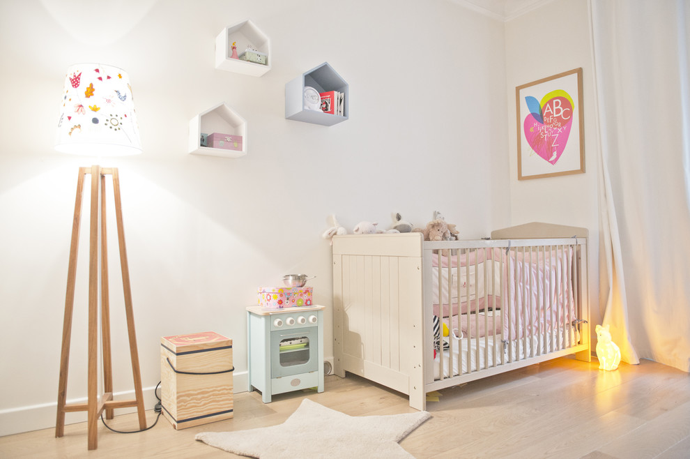 Idées déco pour une chambre de bébé neutre contemporaine de taille moyenne avec un mur blanc, parquet clair et un sol beige.