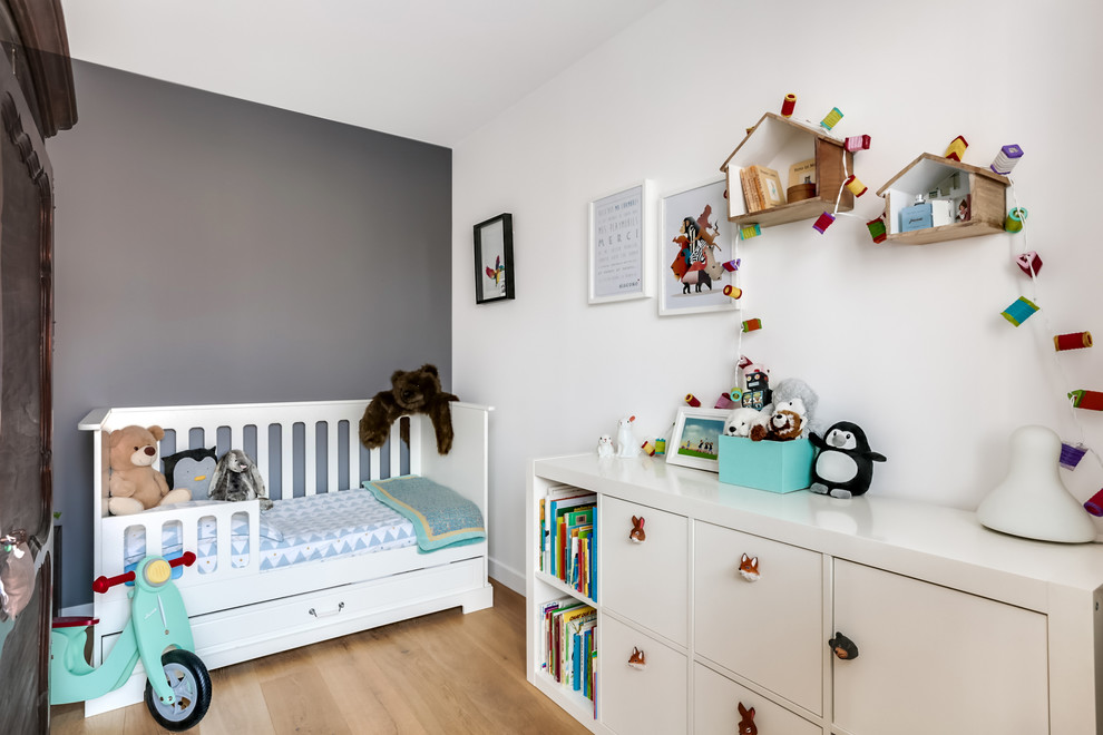 Idée de décoration pour une petite chambre de bébé garçon design avec un mur blanc et parquet clair.