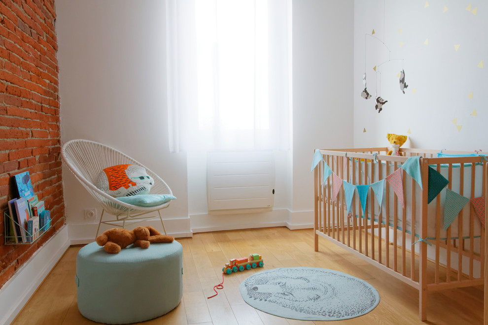 Foto de habitación de bebé neutra escandinava con paredes blancas, suelo de madera clara y suelo beige