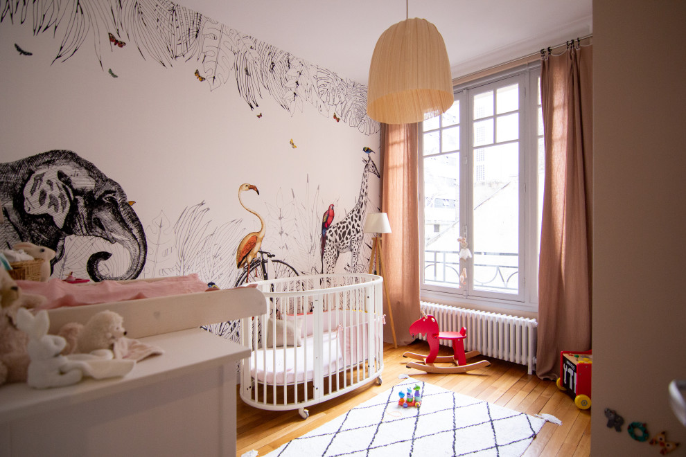 Medium sized contemporary nursery for girls in Paris with beige walls and light hardwood flooring.