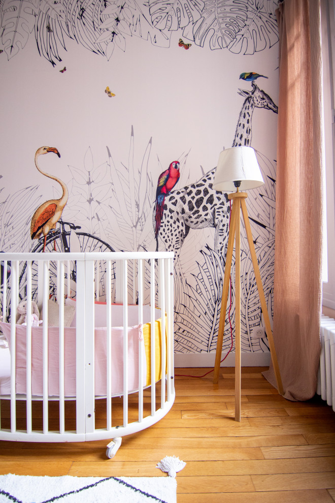 Diseño de habitación de bebé niña actual de tamaño medio con paredes rosas y suelo de madera clara