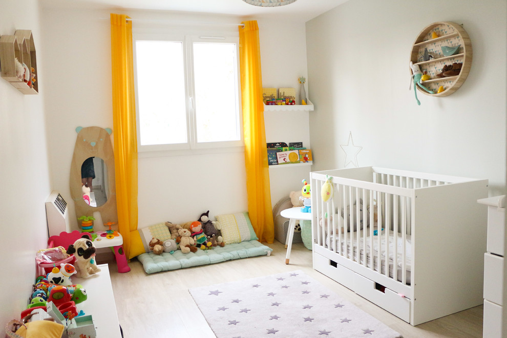Aménagement d'une chambre de bébé fille scandinave avec un mur blanc et parquet clair.