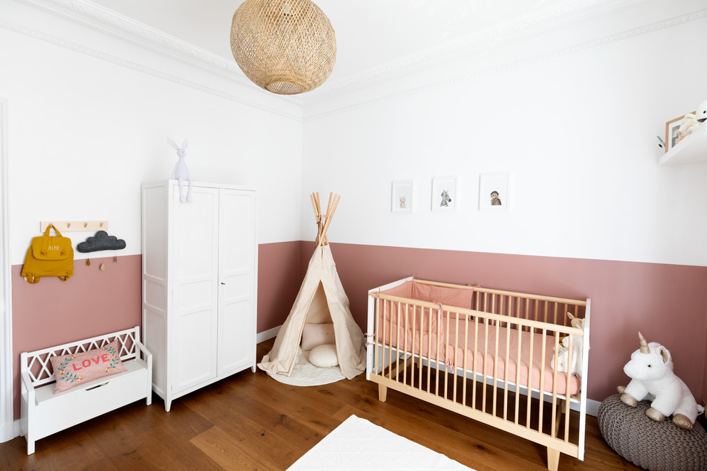 Идея дизайна: комната для малыша среднего размера в современном стиле с розовыми стенами, темным паркетным полом и коричневым полом для девочки