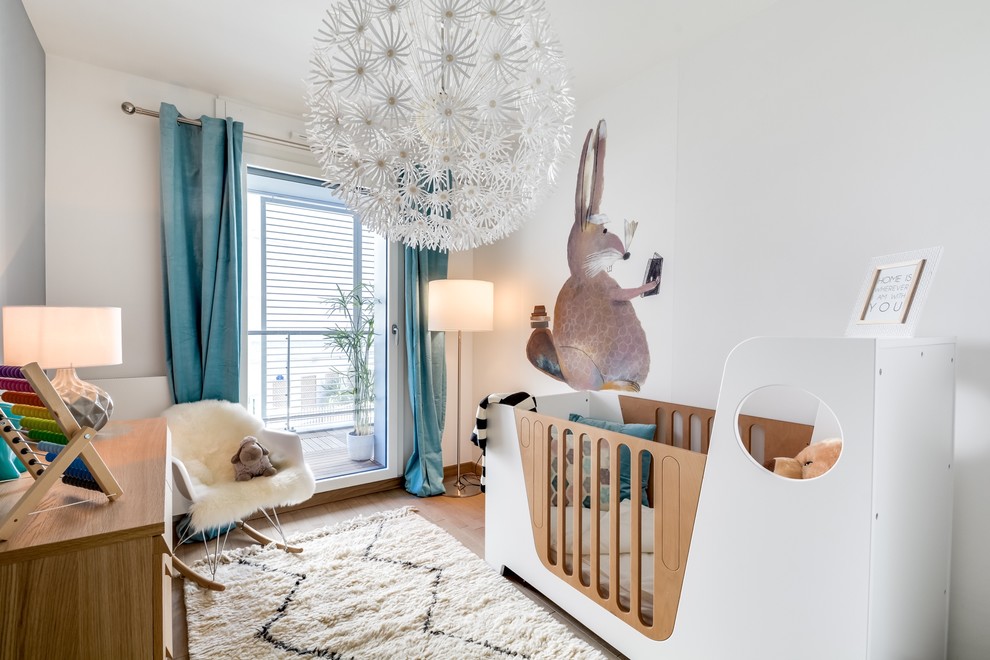 Cette image montre une chambre de bébé neutre design de taille moyenne avec un mur blanc et parquet clair.