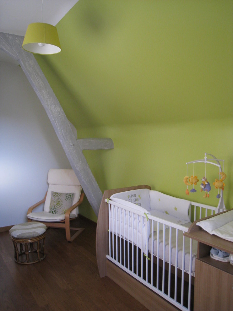Ejemplo de habitación de bebé neutra contemporánea de tamaño medio con paredes verdes y suelo de madera oscura