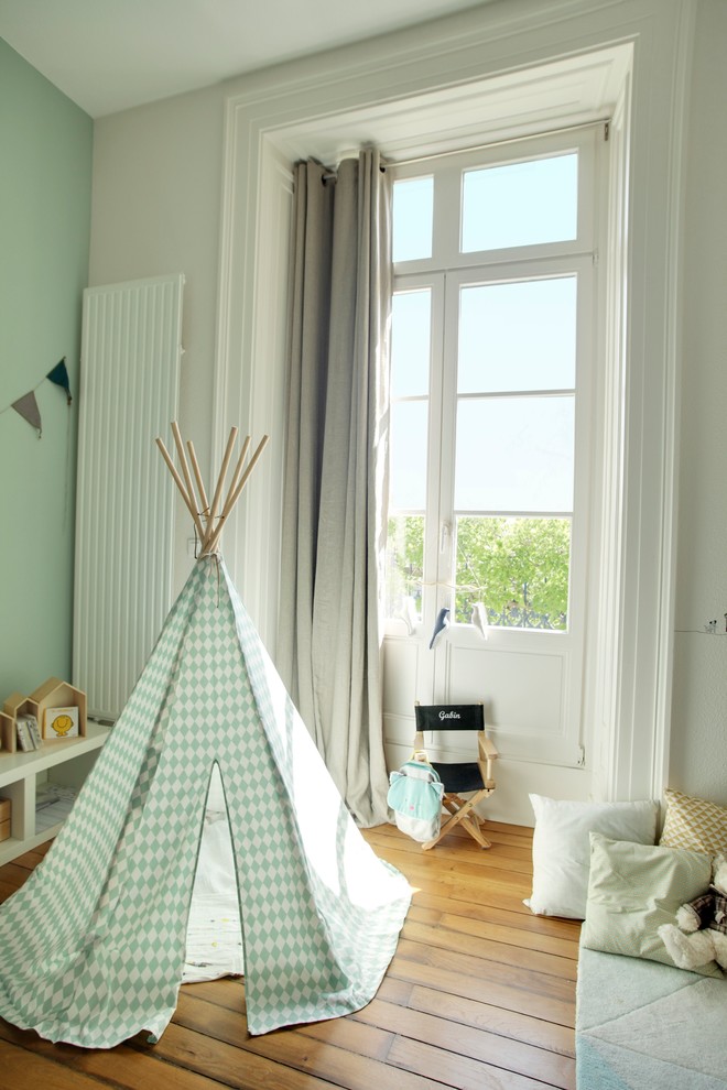 This is an example of a medium sized scandi nursery for boys in Dijon with white walls and medium hardwood flooring.