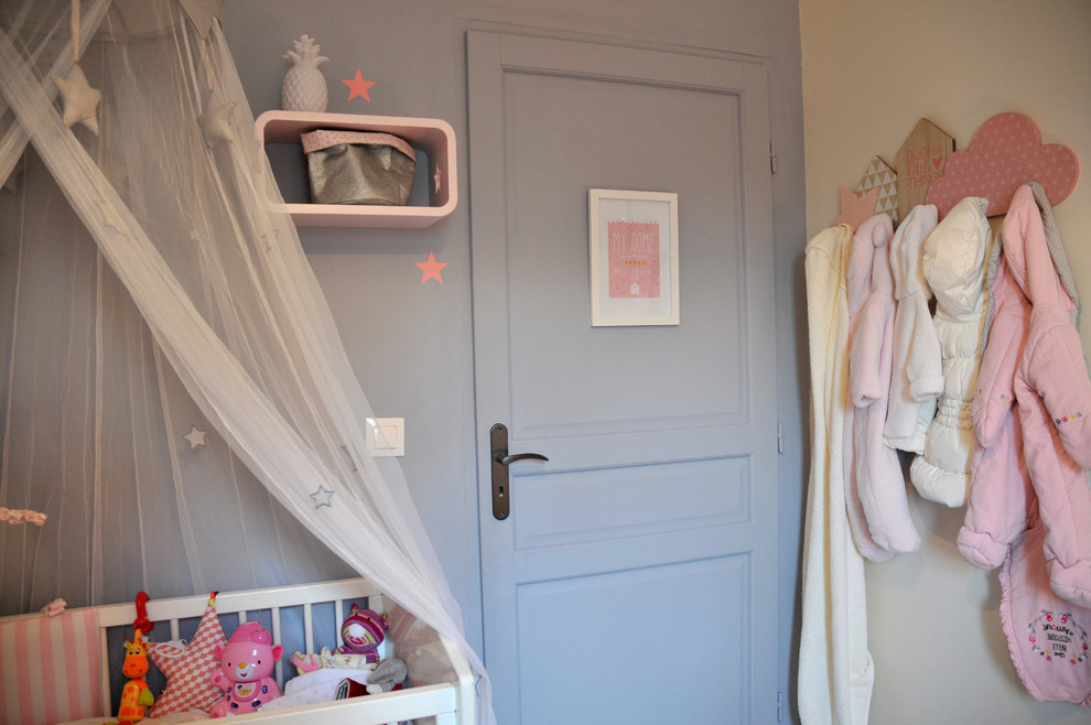 Cette photo montre une petite chambre de bébé fille scandinave avec un mur bleu.