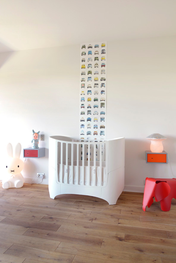 Foto di una cameretta per neonati neutra minimalista di medie dimensioni con pareti bianche e pavimento in legno massello medio