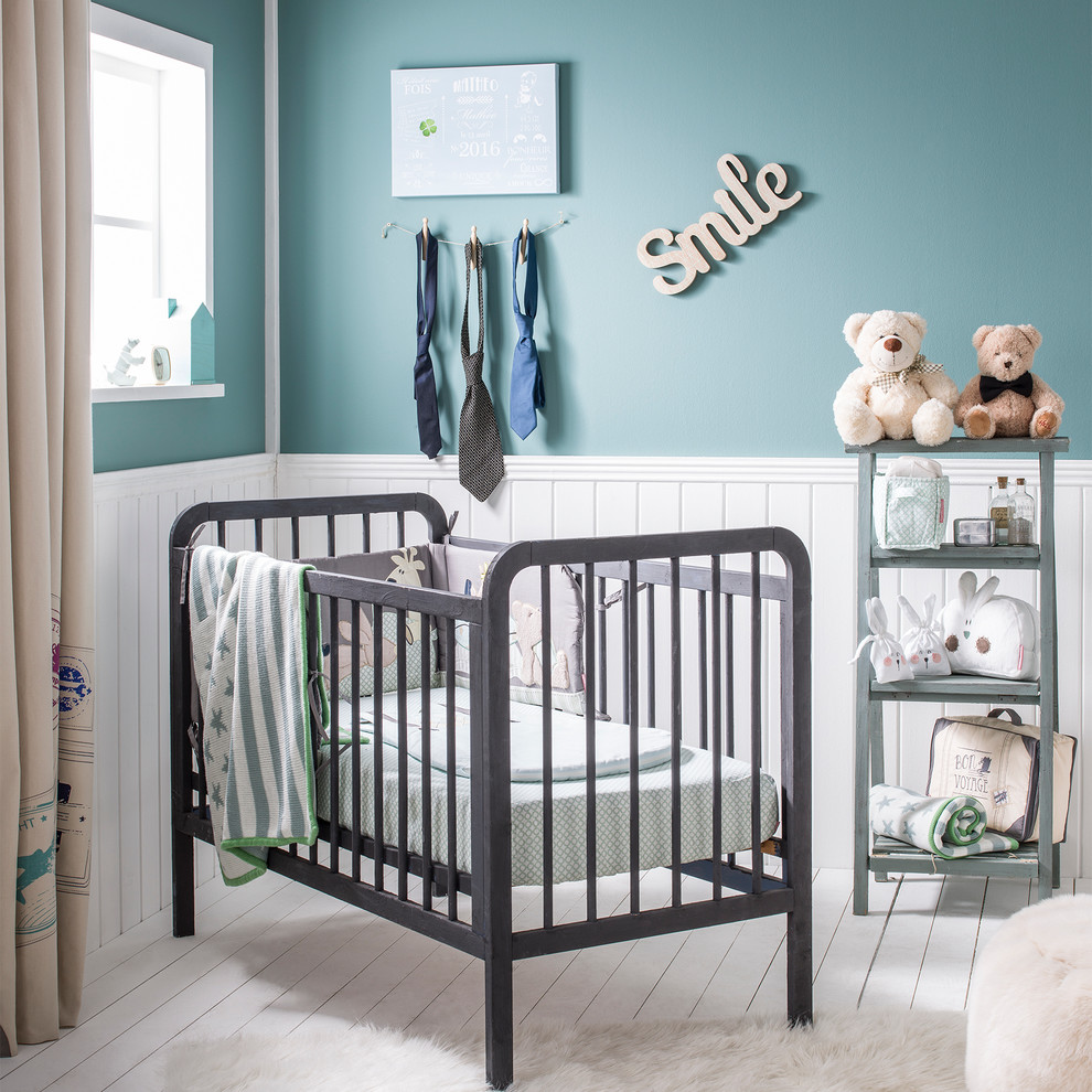 Esempio di una cameretta per neonato minimal di medie dimensioni con pareti blu e pavimento in legno verniciato