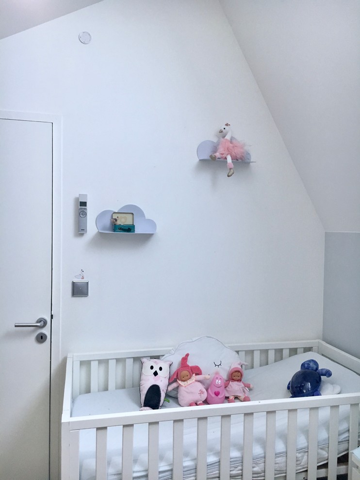Imagen de habitación de bebé niña tradicional de tamaño medio con paredes grises y suelo de madera clara