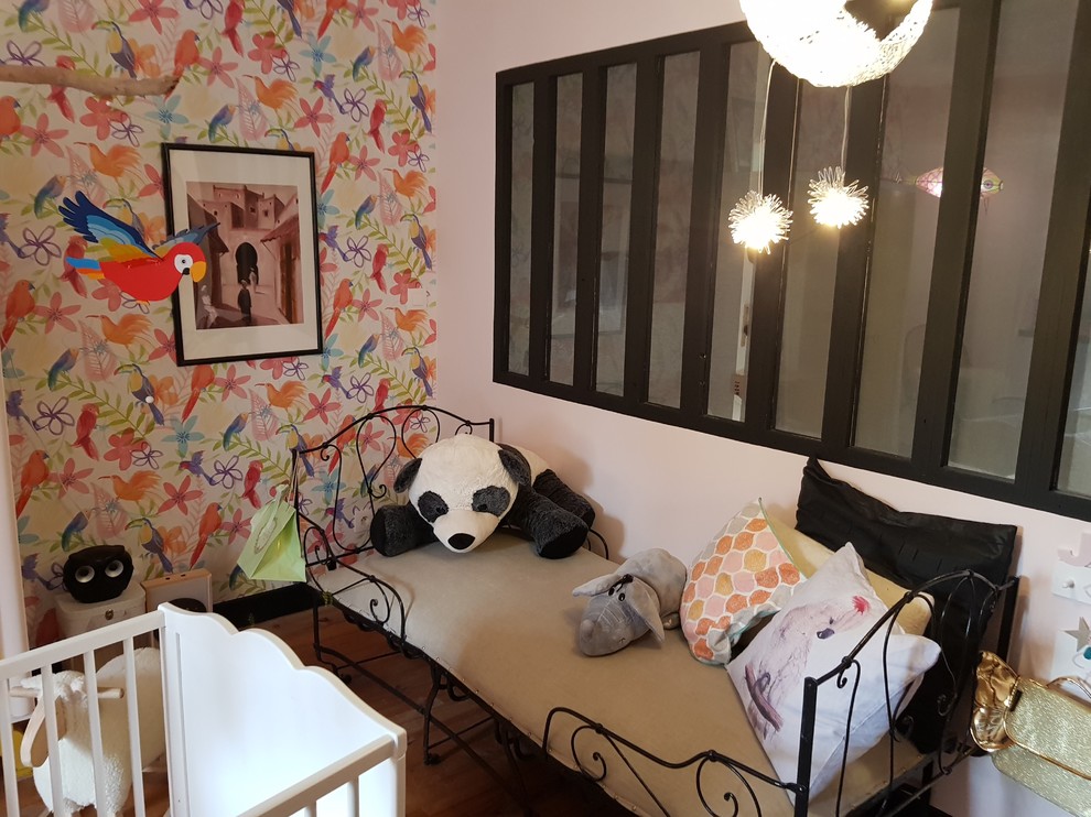 Cette image montre une grande chambre de bébé fille bohème avec un mur rose, parquet clair et un sol beige.