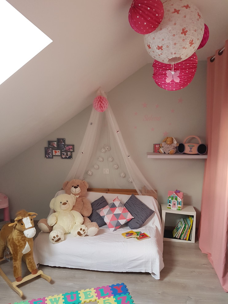 Exemple d'une grande chambre de bébé fille tendance avec un mur rose, sol en stratifié et un sol gris.