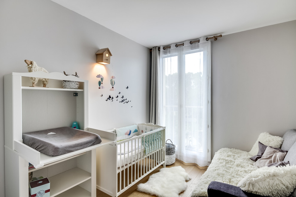 Пример оригинального дизайна: комната для малыша в скандинавском стиле с серыми стенами и паркетным полом среднего тона