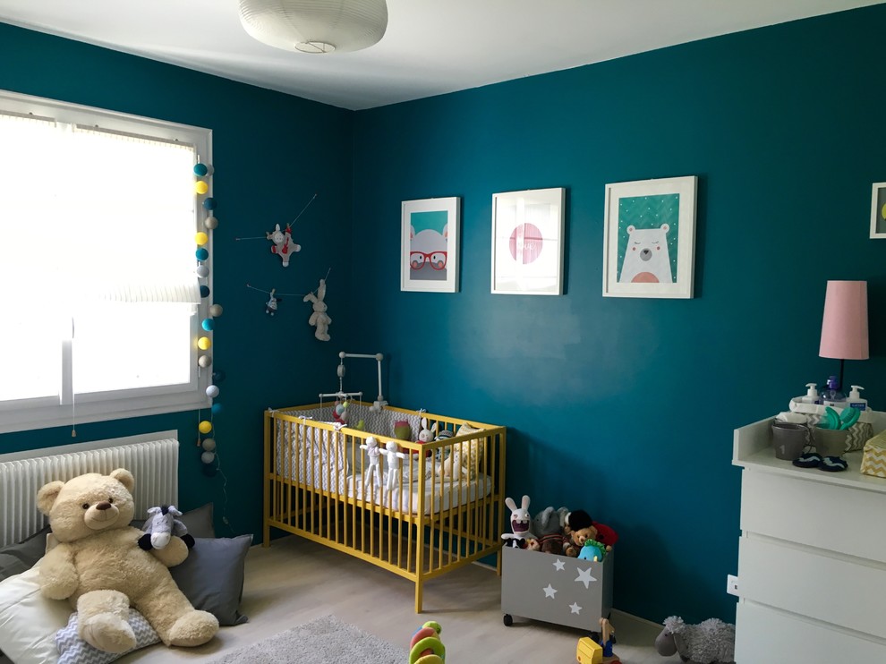Modelo de habitación de bebé neutra moderna de tamaño medio con paredes azules y suelo de madera clara