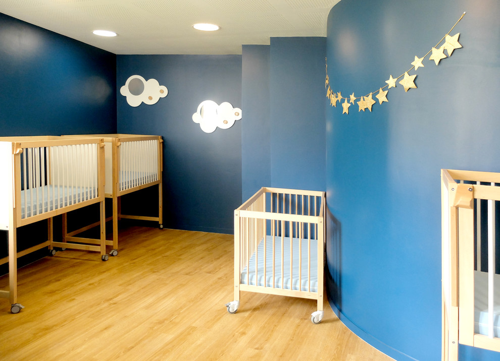 Ispirazione per una cameretta per neonati neutra di medie dimensioni con pareti blu e parquet chiaro