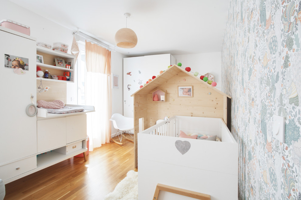 Imagen de habitación de bebé niña contemporánea con paredes multicolor, suelo de madera en tonos medios y suelo marrón