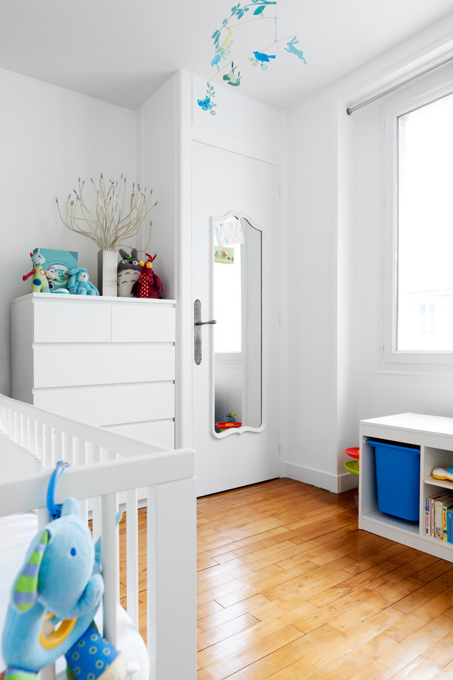 Foto de habitación de bebé niño contemporánea de tamaño medio con paredes blancas, suelo de madera en tonos medios y suelo naranja