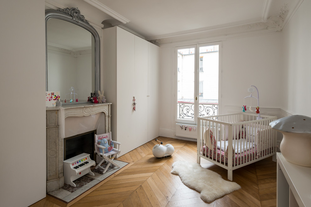 Ejemplo de habitación de bebé neutra actual de tamaño medio con paredes blancas y suelo de madera clara