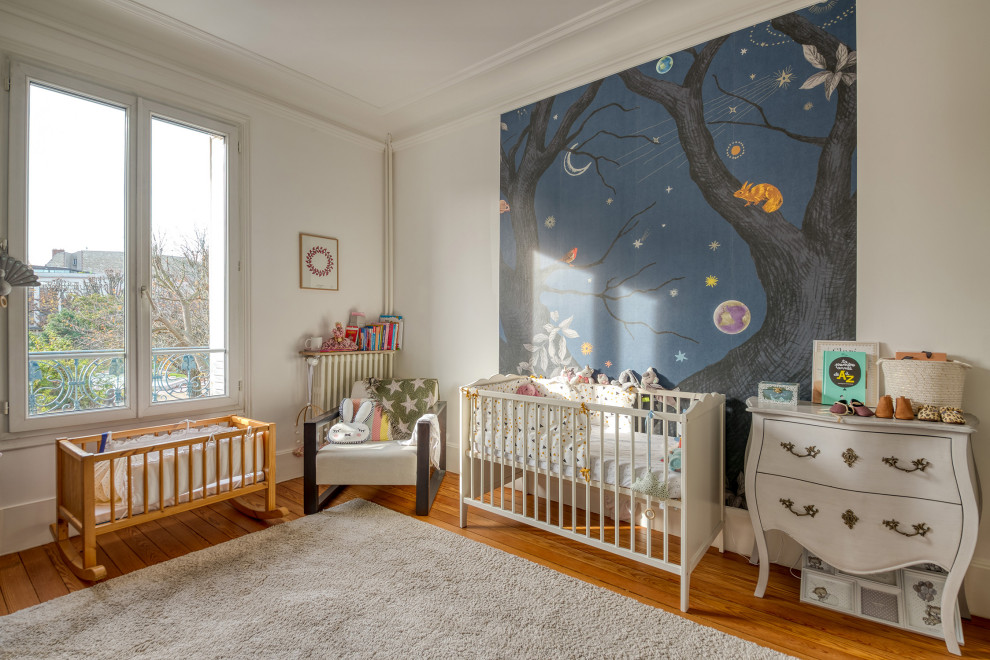 Inspiration pour une chambre de bébé design avec un mur blanc, un sol en bois brun et un sol marron.
