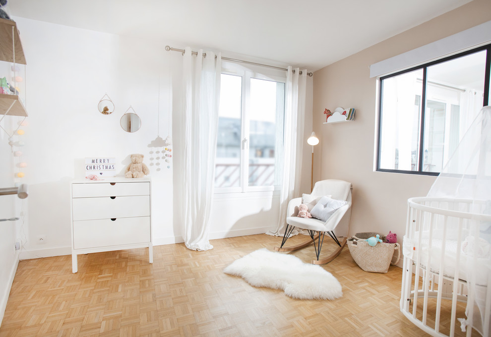 Idées déco pour une chambre de bébé neutre scandinave avec un mur blanc, parquet clair et un sol beige.