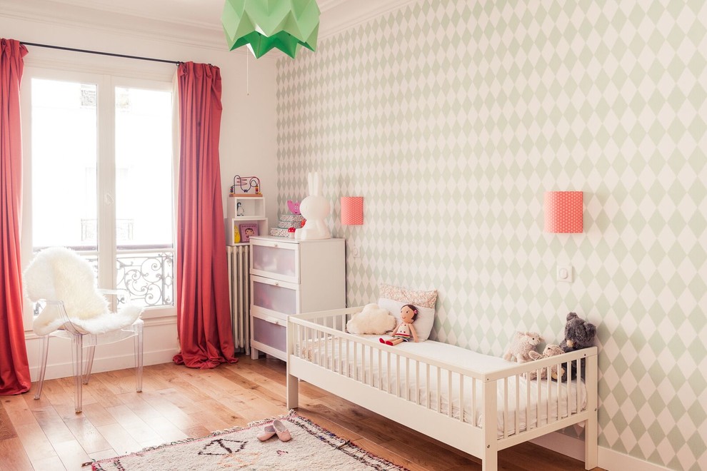Réalisation d'une chambre de bébé fille design avec un mur multicolore et parquet clair.