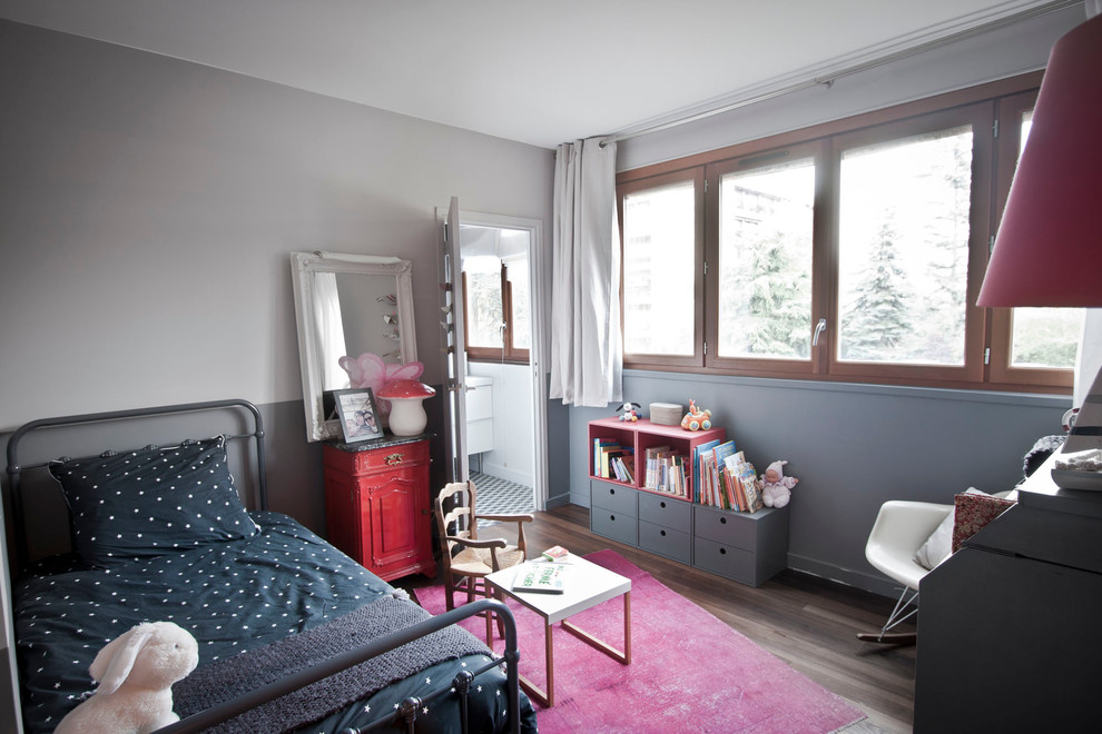 Cette photo montre une petite chambre de bébé fille rétro avec un mur gris et un sol en bois brun.