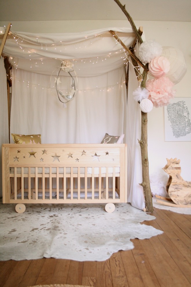 Modelo de habitación de bebé niña romántica con paredes blancas y suelo de madera en tonos medios