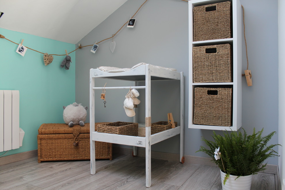 Diseño de habitación de bebé neutra de estilo de casa de campo pequeña con paredes multicolor y suelo de madera clara