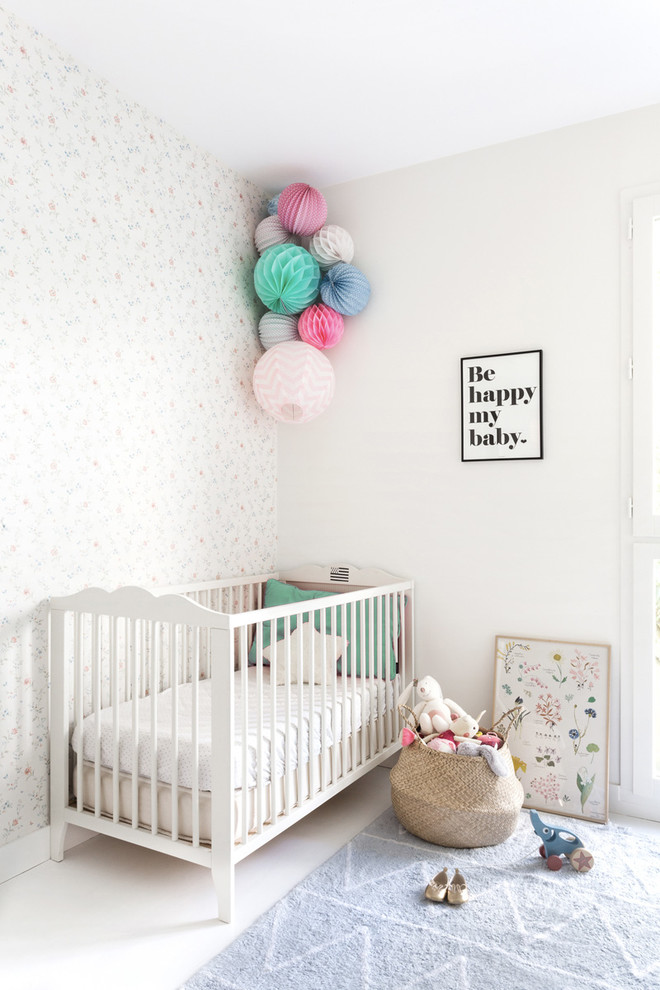 Imagen de habitación de bebé niña moderna de tamaño medio con paredes blancas y suelo de madera pintada