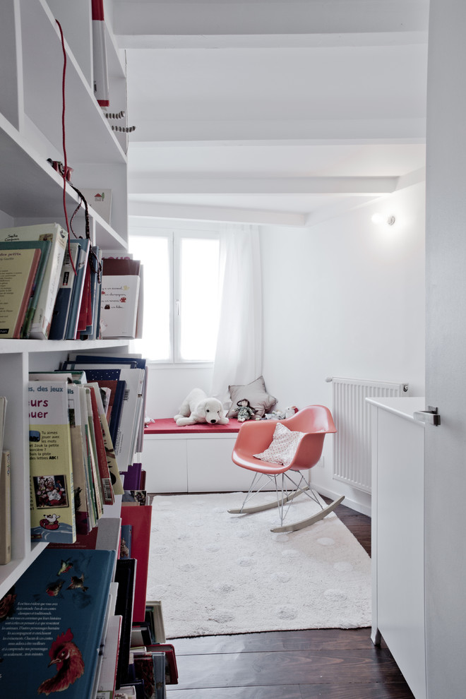 Idée de décoration pour une chambre de bébé neutre design de taille moyenne avec un mur blanc et parquet foncé.
