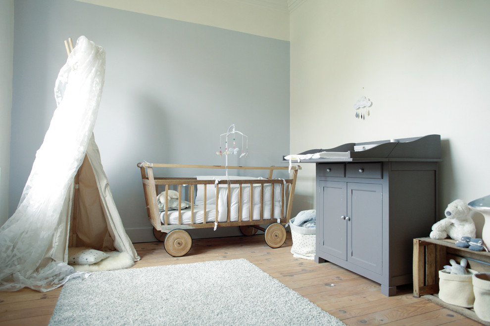Immagine di una cameretta per neonati neutra contemporanea di medie dimensioni con pareti grigie e parquet chiaro