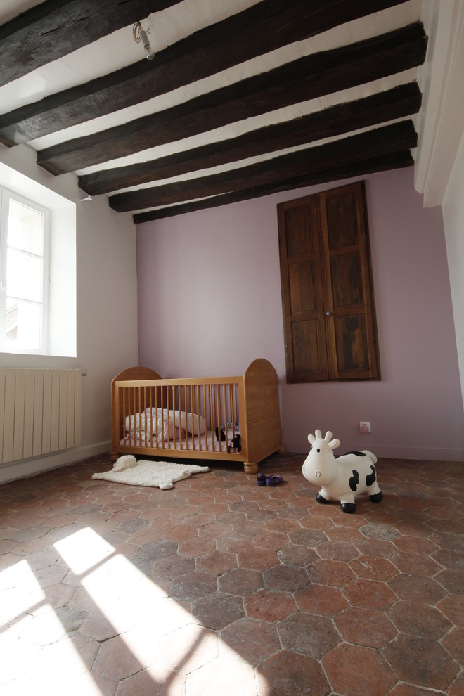 Esempio di una grande cameretta per neonata country con pareti rosa e pavimento in terracotta