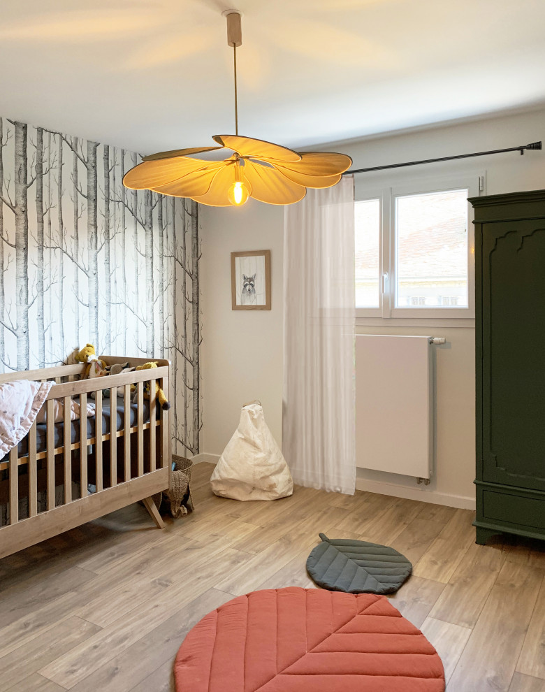 Bild på ett stort minimalistiskt babyrum, med vita väggar, ljust trägolv och brunt golv