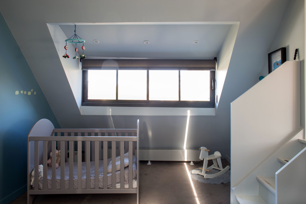 Cette image montre une chambre de bébé neutre minimaliste avec un mur blanc, un sol gris et un plafond voûté.