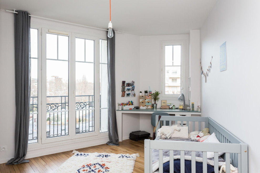 Esempio di una grande cameretta per neonati neutra minimalista con pareti bianche, pavimento beige e pavimento in legno massello medio