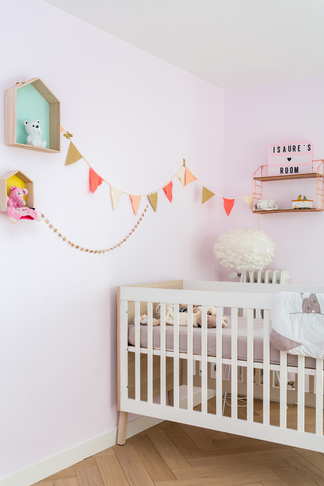 Idée de décoration pour une chambre de bébé fille minimaliste de taille moyenne avec un mur rose, parquet clair et un sol beige.