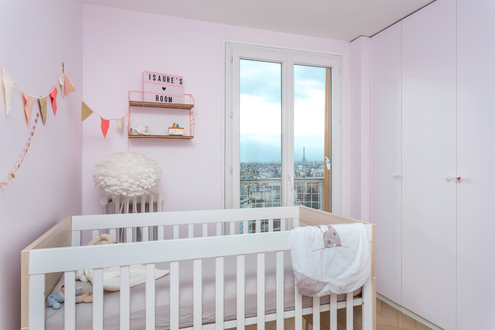 Immagine di una cameretta per neonata moderna di medie dimensioni con pareti rosa, parquet chiaro e pavimento beige