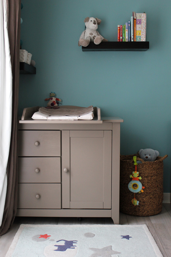 Idee per una piccola cameretta per neonato design con pareti blu e parquet chiaro