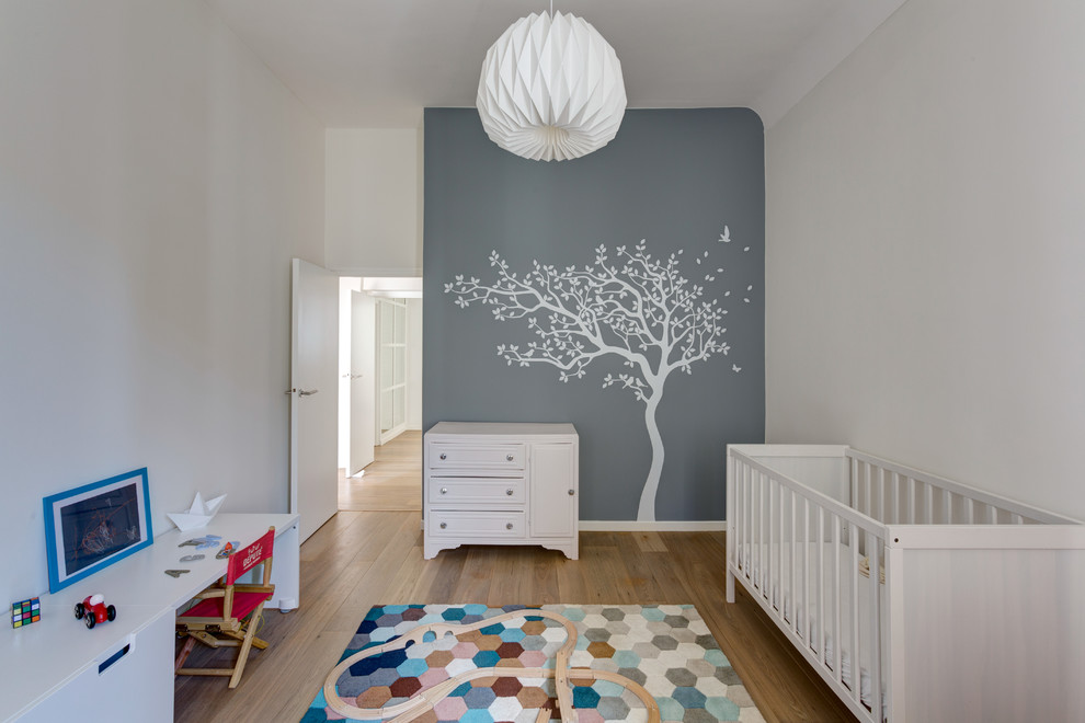 Mittelgroßes, Neutrales Nordisches Babyzimmer mit grauer Wandfarbe, braunem Holzboden und braunem Boden in Paris