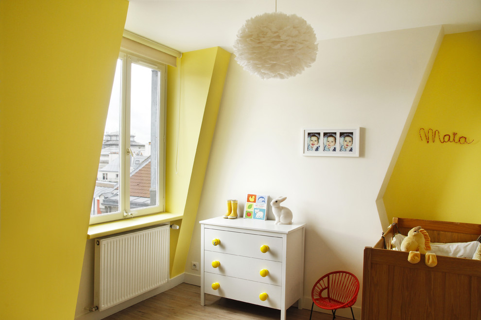Foto på ett mellanstort funkis könsneutralt babyrum, med gula väggar och ljust trägolv