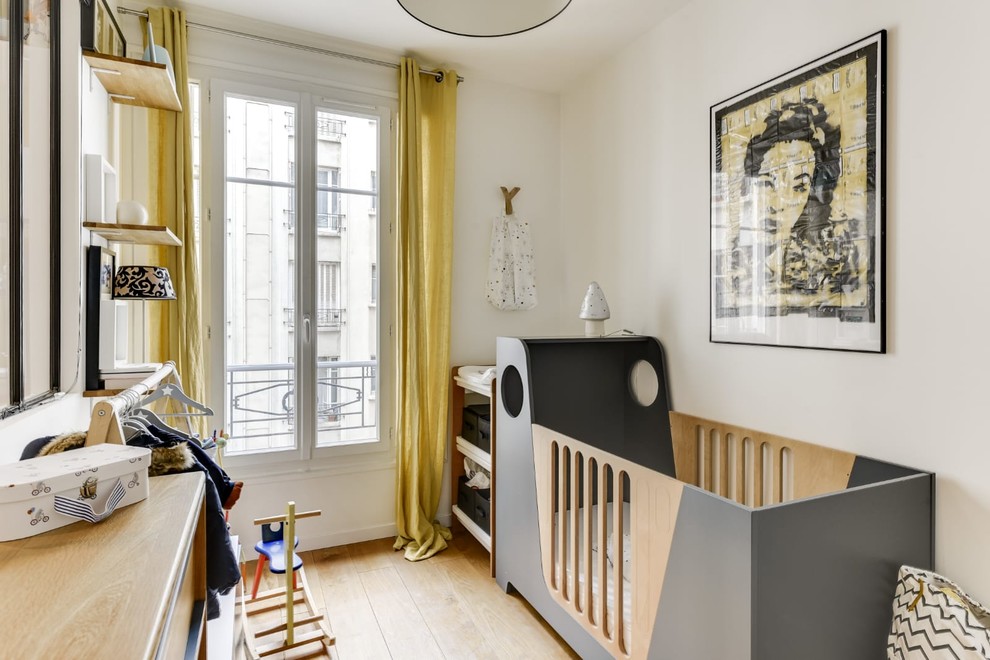 Cette image montre une petite chambre de bébé garçon avec un mur blanc et parquet clair.