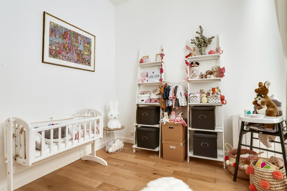 Exemple d'une chambre de bébé fille scandinave avec un mur blanc, un sol en bois brun et un sol marron.