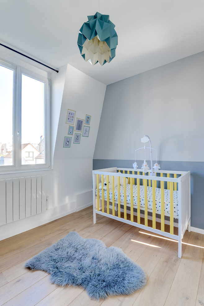 Ispirazione per una grande cameretta per neonato moderna con pareti blu e parquet chiaro