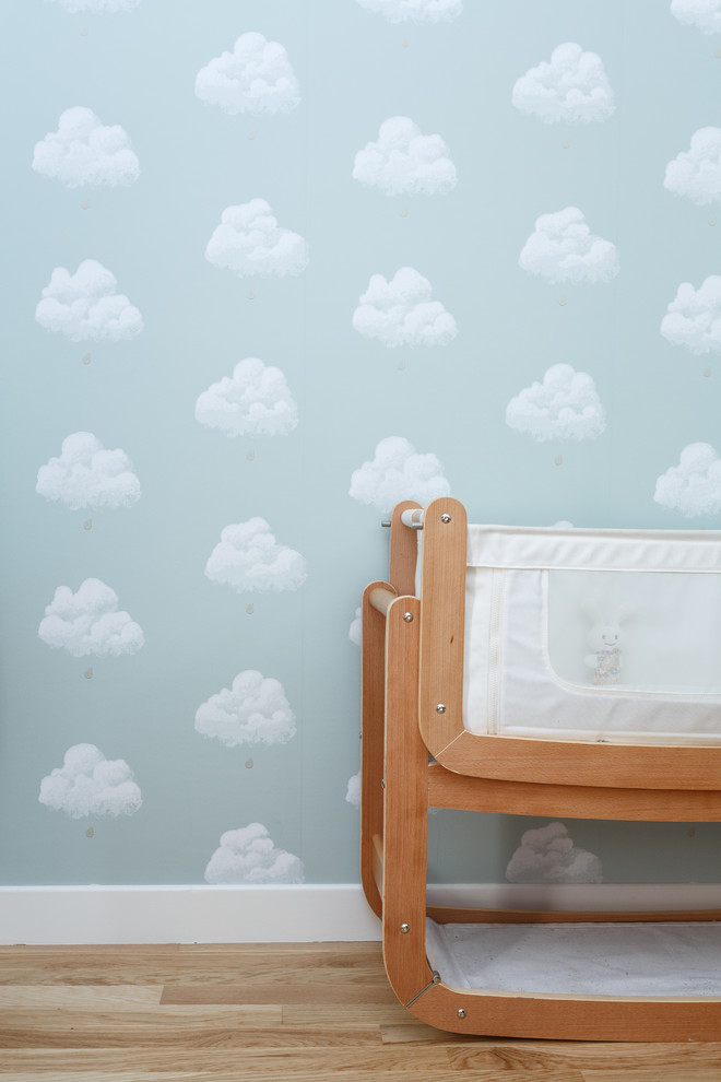 Aménagement d'une chambre de bébé neutre moderne de taille moyenne avec un mur bleu, un sol en bois brun et un sol beige.