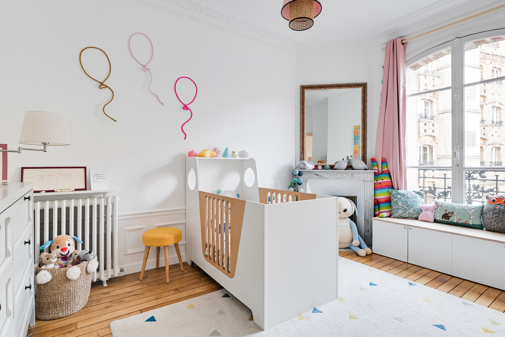 Inspiration for a scandinavian nursery for girls in Paris with white walls, light hardwood flooring and a dado rail.