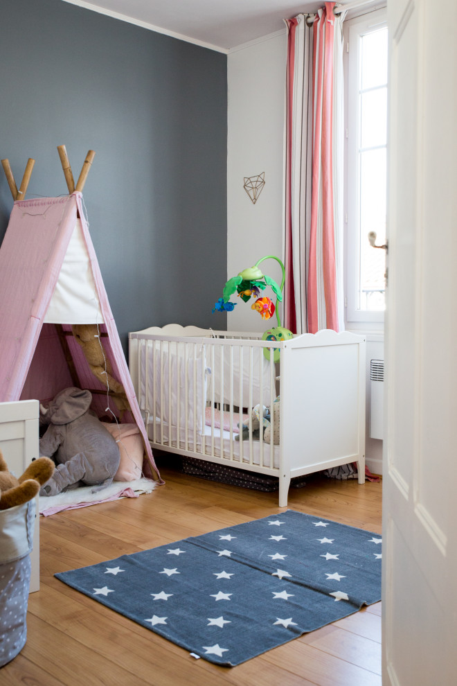 Réalisation d'une chambre de bébé fille tradition de taille moyenne avec un mur gris, un sol en bois brun et un sol marron.
