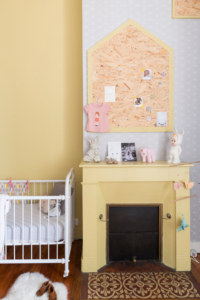 Ejemplo de habitación de bebé neutra escandinava de tamaño medio con paredes amarillas y suelo de madera en tonos medios