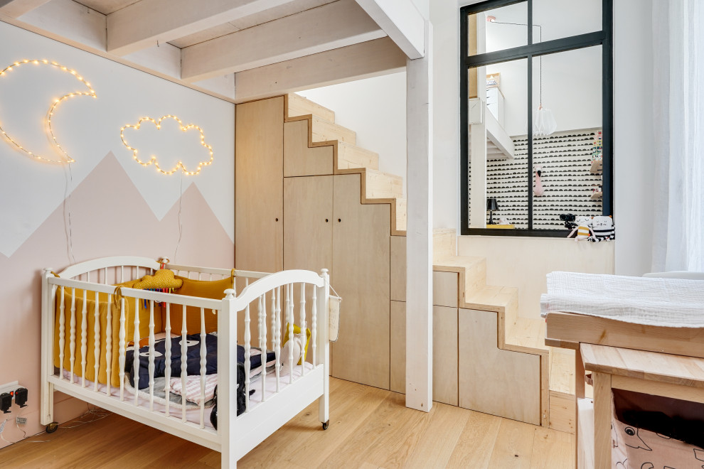 Design ideas for a contemporary nursery for girls in Bordeaux with pink walls, light hardwood flooring, beige floors and a feature wall.