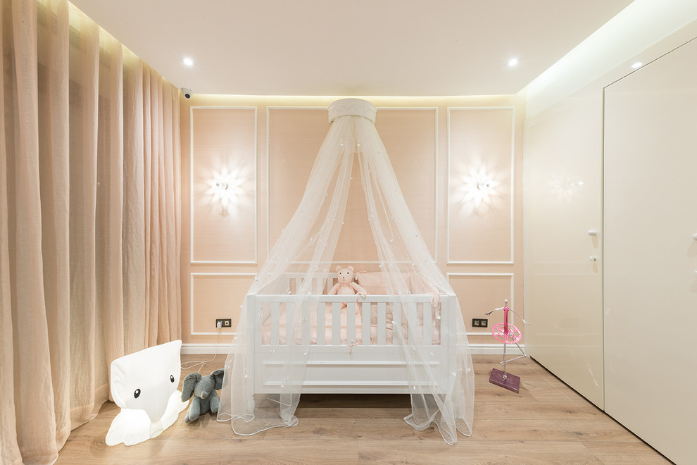 Exemple d'une chambre de bébé fille chic de taille moyenne avec un mur rose, un sol en bois brun et un sol beige.
