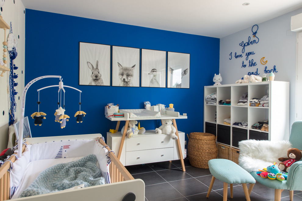 Cette photo montre une chambre de bébé neutre tendance avec un mur bleu et un sol gris.